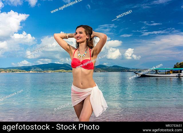 Attractive young woman wearing trendy swimwear and accessories while posing on a tropical beach in Komodo Island during summer vacation in Indonesia