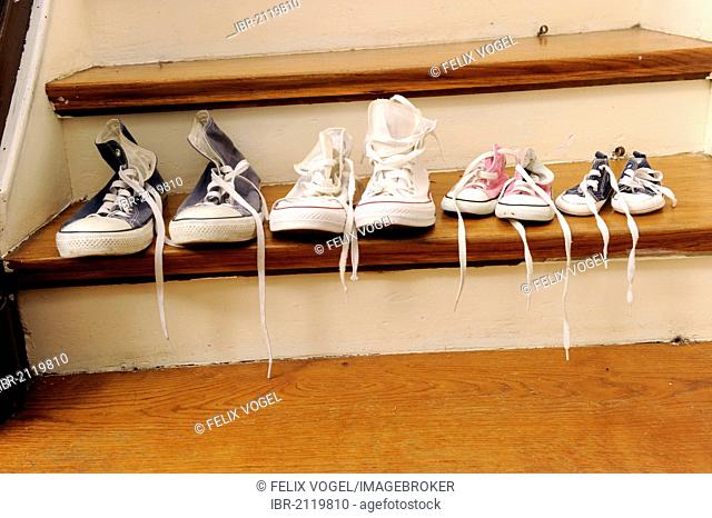 Sport shoes of a family with two children, lined up on a stair