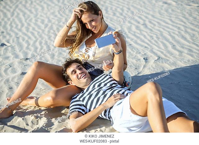 Happy affectionate young couple taking a selfie on the beach
