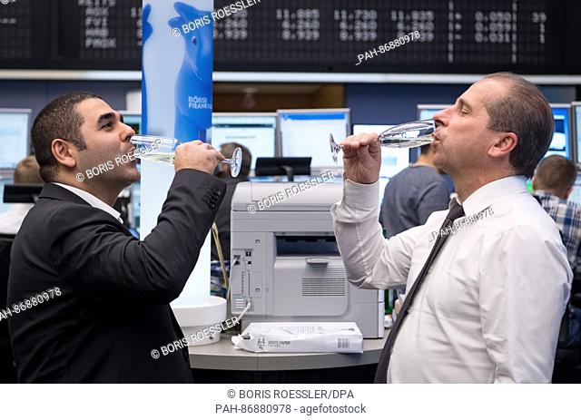 Two stockbrokers drink glasses of prosecco in the trading room of the stockmarket in Frankfurt am Main, Germany, 30 December 2016