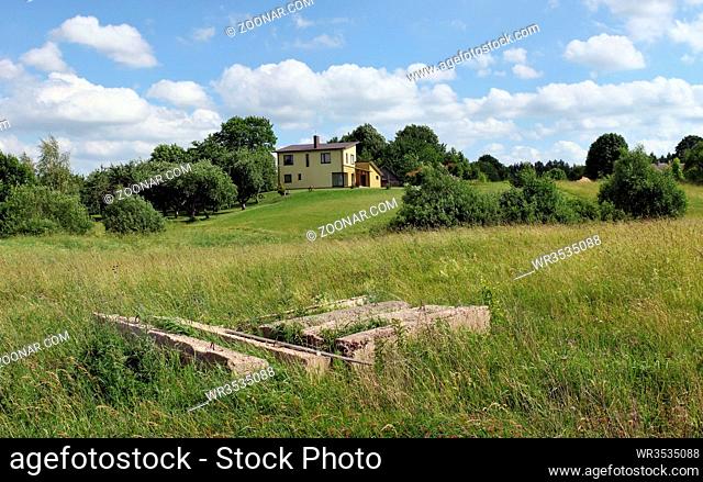 VILNIUS, LITHUANIA - JUNE 18, 2016: The base of the destroyed rural house near a new modern cottage in public garden association Kalorija near the Lithuanian...