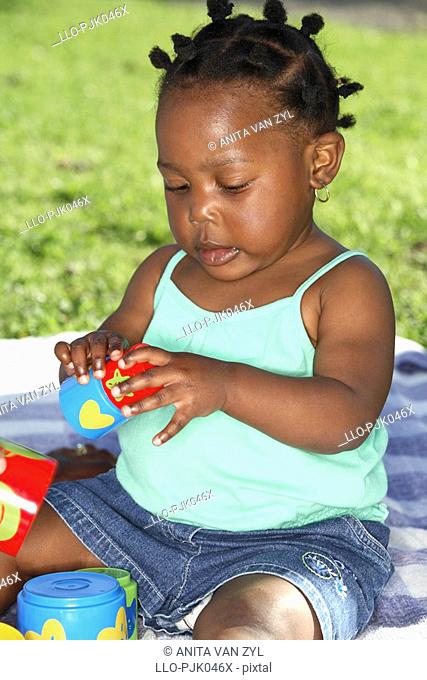 Baby girl playing with building blocks. Dewaal Park, Cape Town, Western Cape Province, South Africa