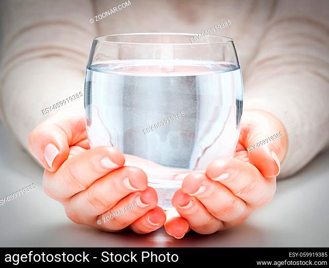 A glass of clean mineral water in woman#39;s hands. Concept of environment protection, healthy drink
