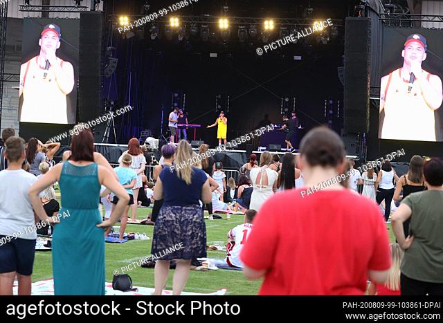 09 August 2020, Thuringia, Erfurt: Spectators stand on the grass and on blankets at the summer open air of German singer Pietro Lombardi in the...