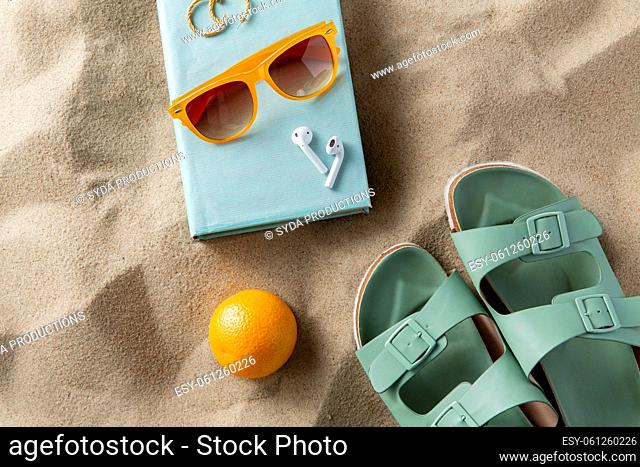 slippers, orange, earbuds and sunglasses on beach