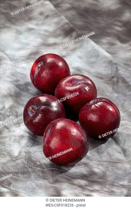 Red plums on grey background, close up