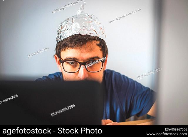 Young man is wearing aluminum cap, conspiracy theory concept