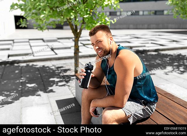 sportsman with earphones and bottle in city