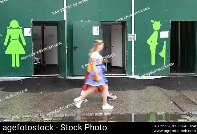 26 September 2022, Bavaria, Munich: Two ladies walk past toilets at the Oktoberfest. The Wiesn takes place from September 17 to October 3, 2022