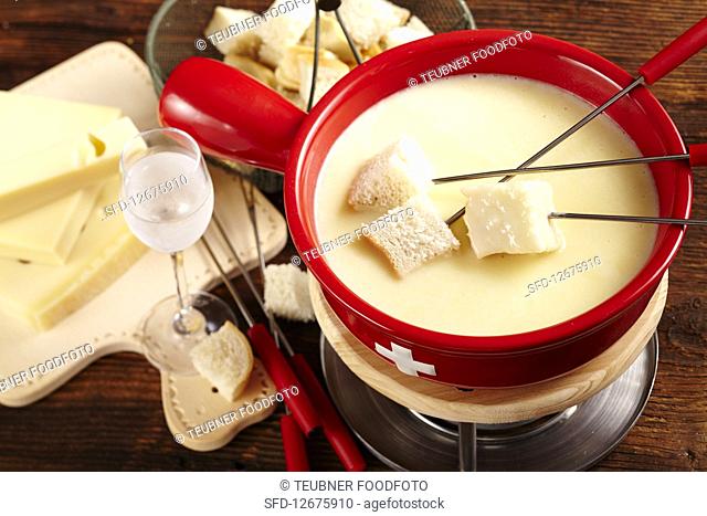 Swiss cheese fondue in a rechaud with a glass of kirschwasser and bread
