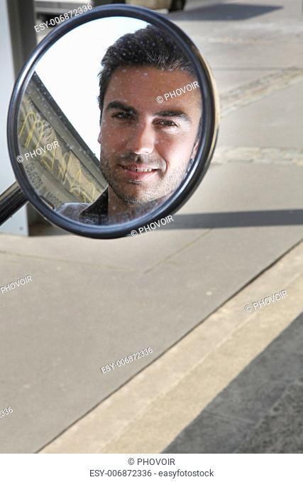 Man looking in the wing mirror of a scooter