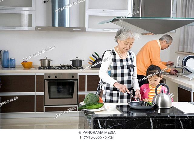Senior couple and granddaughter cooking in kitchen