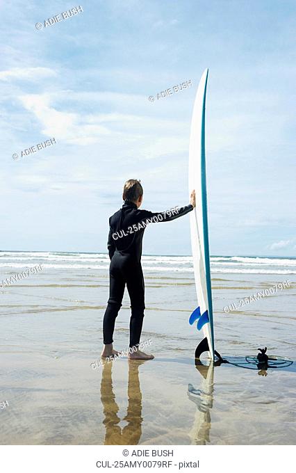 Boy looking out to sea with surf board