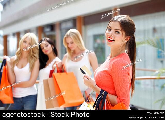 Young beautiful happy women with shopping bags and credit card in mall