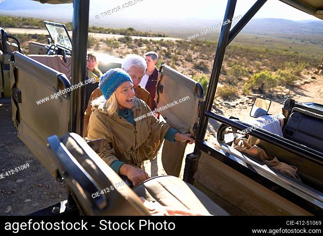 Happy senior woman getting into safari off-road vehicle