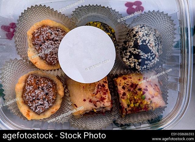 A straight down view of homemade cupcakes with buttercream frosting and sprinkles, displayed in a small plastic tub with a blank white sticker for copy space