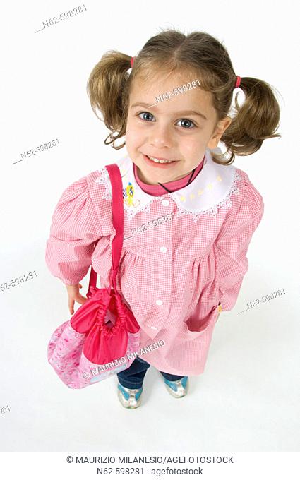 Little girl with pigtails top view, she wearing a pink apron to the kindergarten and her backpack on her shoulder