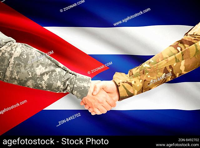 Soldiers shaking hands with flag on background - Cuba