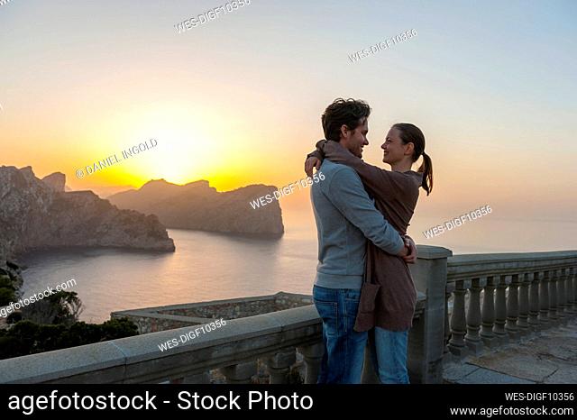 Couple standing on terrace by sunset hugging each other, Cap Formentor, Mallorca, Spain