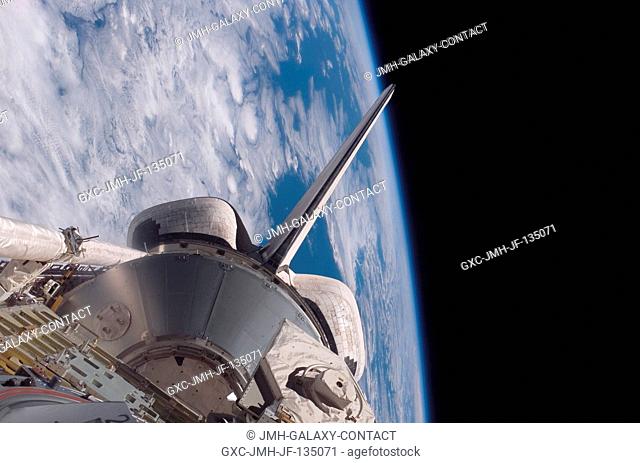 Backdropped by the blackness of space and Earth's horizon, Space Shuttle Discovery's aft cargo bay, its vertical stabilizer and orbital maneuvering system (OMS)...