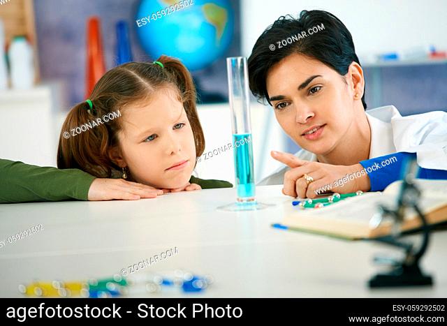 Pupil and teacher looking at test tube in chemisty class at elementary school. Teacher explaining