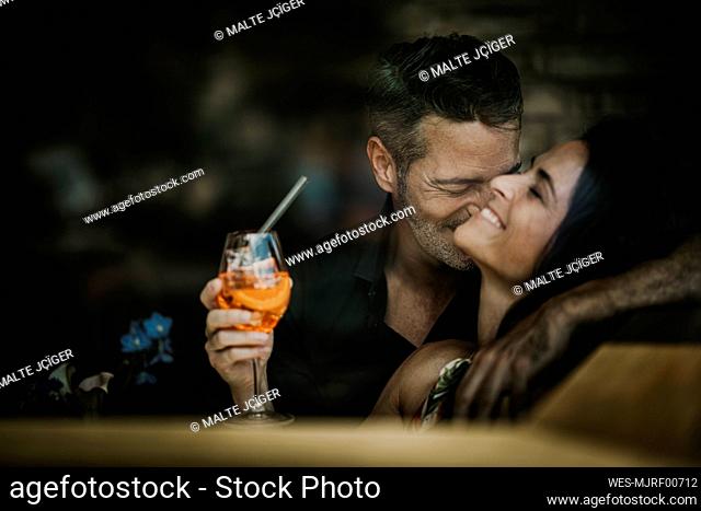 Boyfriend enjoying with girlfriend holding drink in restaurant