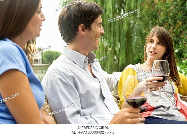 Friends relaxing outdoors with glass of wine