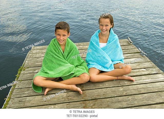 Children wrapped in towels on dock