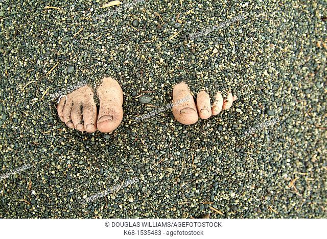 Toes showing from feet buried in sand