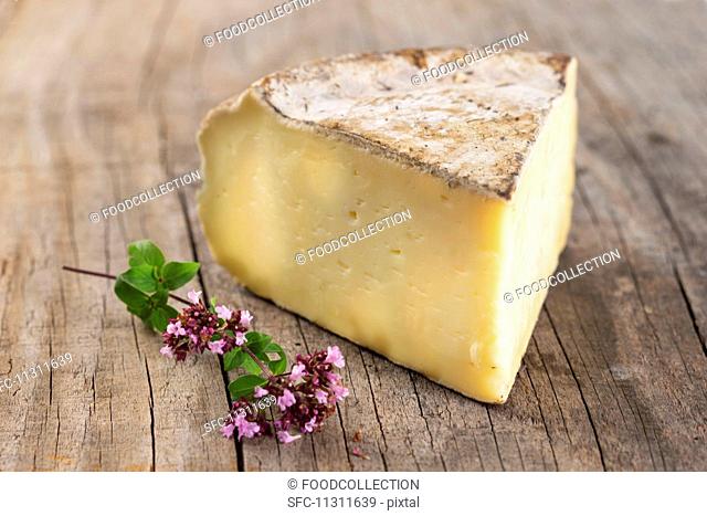 A slice of Tomme De Savoie cheese on wooden surface