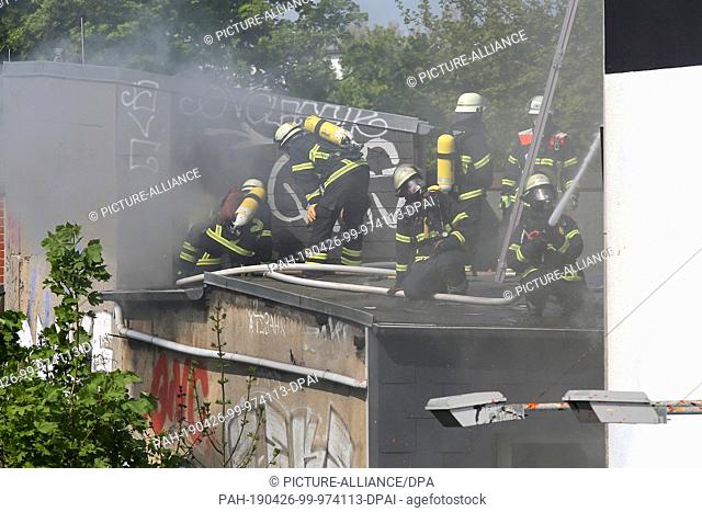 26 April 2019, Hamburg: Firefighters are on a roof extinguishing a fire. A fire had broken out in a six-storey house in the Schanzenviertel