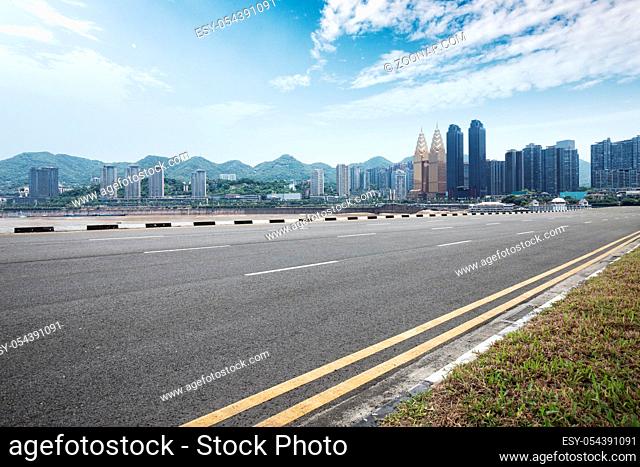 empty asphalt road and modern buildings in nanjing near river in blue sky