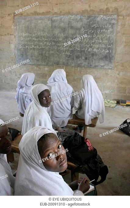 Tanji Village. African Muslim girls wearing white headscarves attending a class at the Ousman Bun Afan Islamic school. Girls in foreground looking back towards...