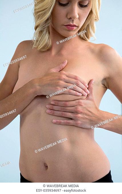 Young woman touching breast while examining lumps