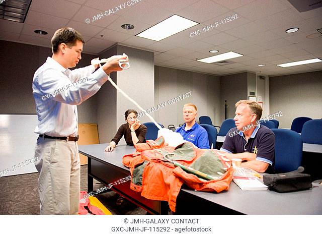 Crew trainer Adam Flagan (standing) briefs STS-133 crew members during a classroom session of water survival training at NASA's Johnson Space Center