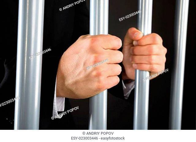 Close-up Of Businessman Holding Bars In Jail