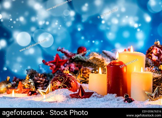 Christmas candles with traditional decorative stars , red baubles , pine cones and green branches on snow