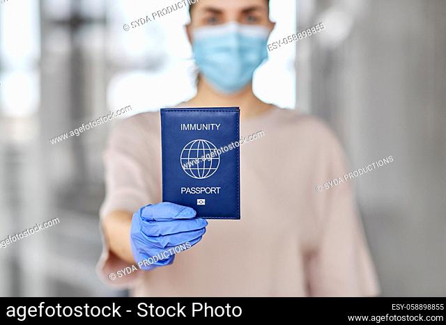 woman in mask and gloves holding immunity passport