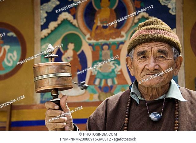 Senior man with a prayer wheel in a monastery, Likir Monastery, Ladakh, Jammu and Kashmir, India