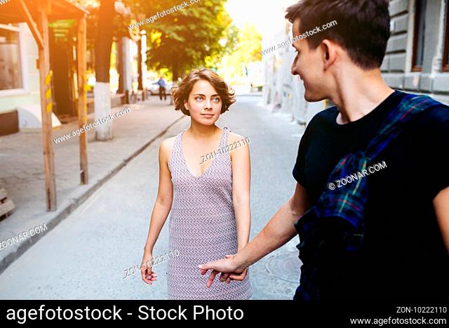 happy young couple of a handsome man and attractive woman walking on the street holding hands
