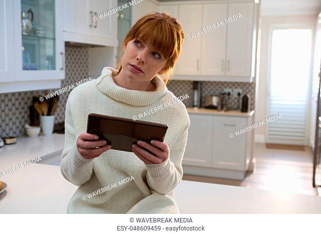 Woman using digital tablet in kitchen at home
