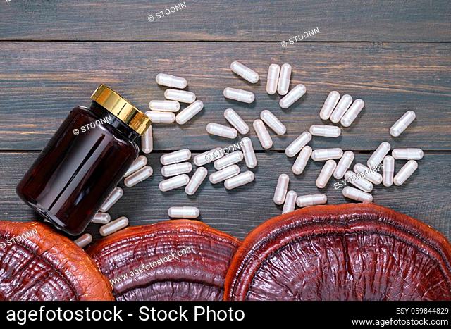 Ling zhi mushroom, Ganoderma lucidum mushroom and capsule with bottle mockup on wooden floor