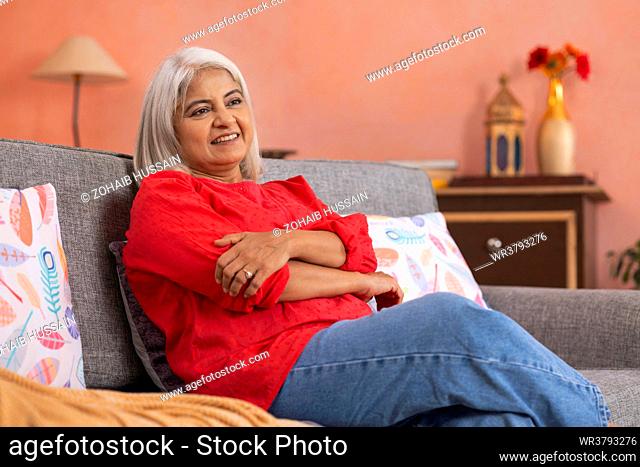 Portrait of an old woman relaxing on sofa in living room