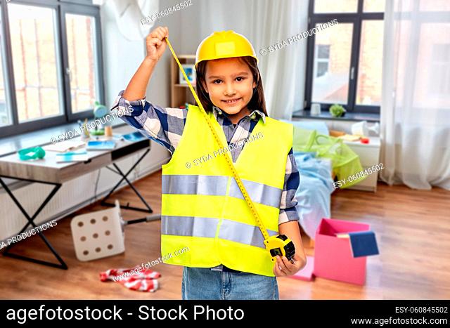 girl in construction helmet with ruler at home