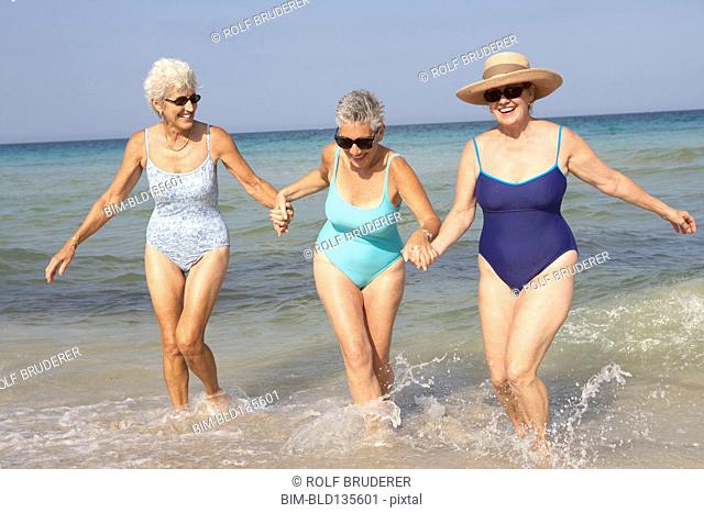 Senior women walking in waves on beach