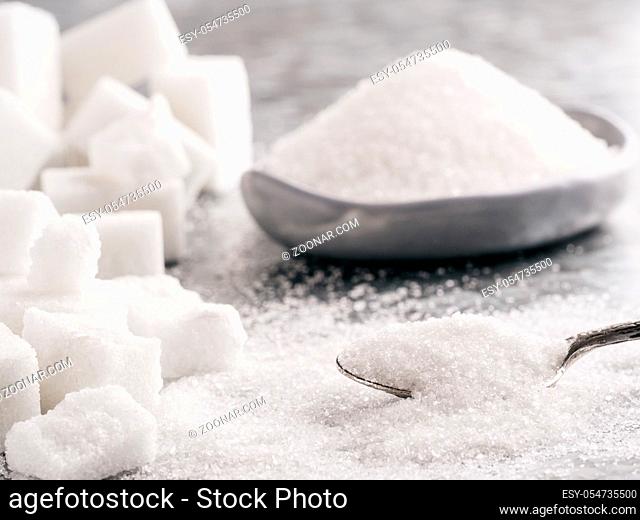 Sugar background. Sugar cubes, granulated sugar in spoon and plate. White sugar on gray galvanized iron background. Copy space