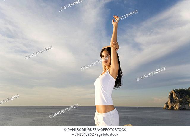 Portrait of a brunette woman breathing fresh air by the sea smiling at camera