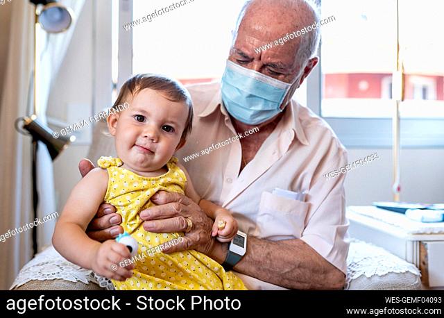 Grandfather with protective mask and baby girl at home