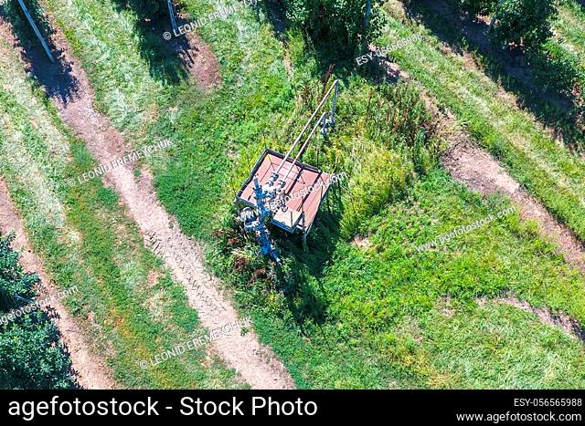 The well in the apple orchard, top view. Equipment of an oil well. Shutoff valves and service equipment