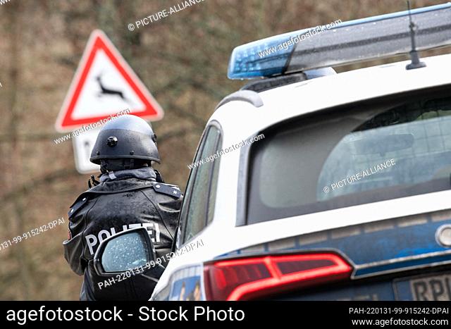 31 January 2022, Rhineland-Palatinate, Mayweilerhof: Police officers stand at a barricade on county road 22, about a kilometer from the scene where two police...